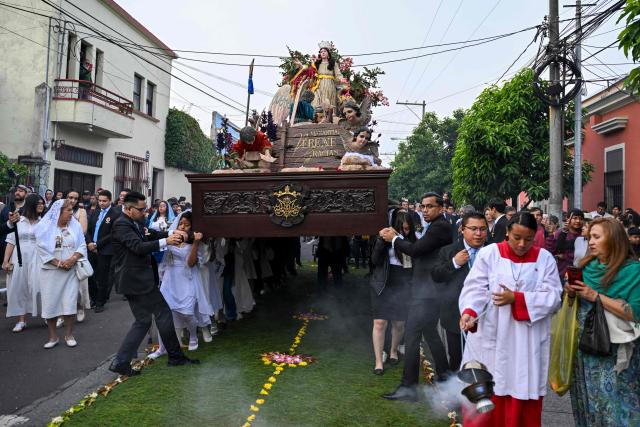 Catholic faithful carry the image of the Virgin of the Assumption as they take part in a parade to celebrate the day of the city's patron saint in Guatemala City on August 15, 2025. (Photo by JOHAN ORDONEZ / AFP)