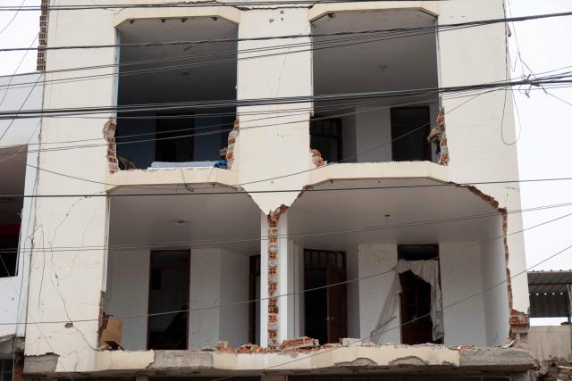 The damaged facade of a house that suffered a dynamite attack caused by clashes between criminal organizations is pictured in the city of Trujillo, northern Peru on August 15, 2025. At least three people were injured and a hundred homes were affected by a dynamite attack in the Peruvian city of Trujillo, which took place during clashes between criminal organisations, authorities reported on Friday. (Photo by AFP)