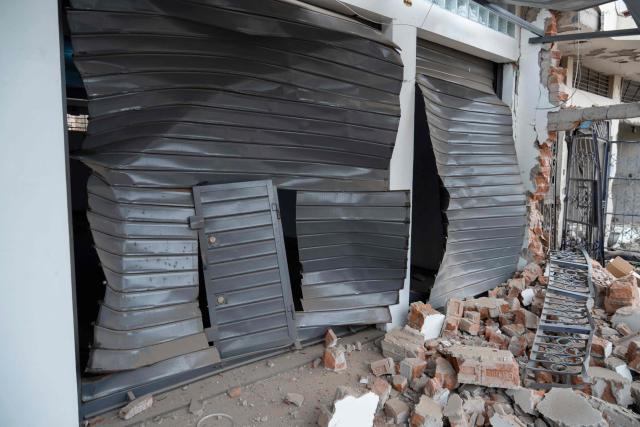 Damaged roll-up curtain doors of a house that suffered a dynamite attack caused by clashes between criminal organizations are pictured in the city of Trujillo, northern Peru on August 15, 2025. At least three people were injured and a hundred homes were affected by a dynamite attack in the Peruvian city of Trujillo, which took place during clashes between criminal organisations, authorities reported on Friday. (Photo by AFP)