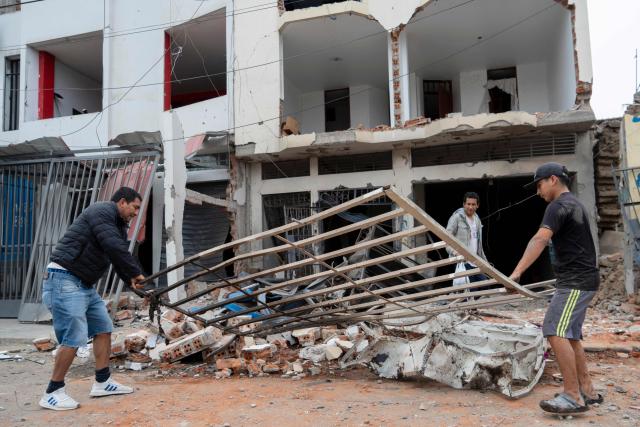 People remove the debris in front of a house that suffered a dynamite attack caused by clashes between criminal organizations in the city of Trujillo, northern Peru on August 15, 2025. At least three people were injured and a hundred homes were affected by a dynamite attack in the Peruvian city of Trujillo, which took place during clashes between criminal organisations, authorities reported on Friday. (Photo by AFP)