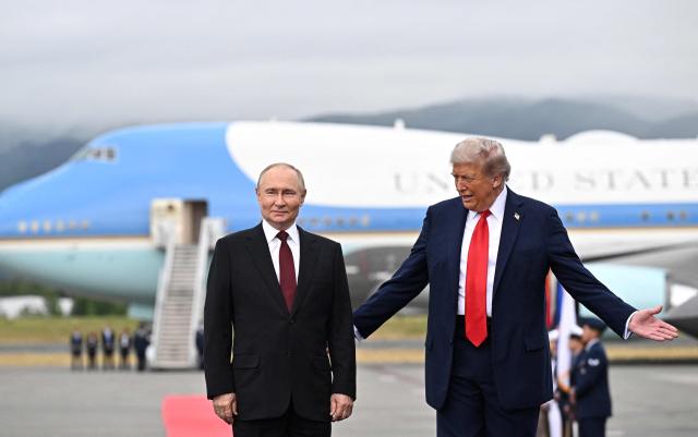 In this pool photograph distributed by the Russian state agency Sputnik, US President Donald Trump and Russian President Vladimir Putin pose for photos during a US-Russia summit on Ukraine at Joint Base Elmendorf-Richardson in Anchorage, Alaska, on August 15, 2025. (Photo by Sergey Bobylev / POOL / AFP)