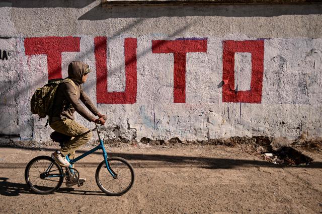 A man rides a bike in front of a mural for Bolivia's presidential candidate from the "Alianza Libre" (Free Alliance) coalition, Jorge "Tuto" Quiroga Ramirez, in La Paz on August 15, 2025. Bolivia will hold a presidential election on August 17, 2025. (Photo by Martin BERNETTI / AFP)