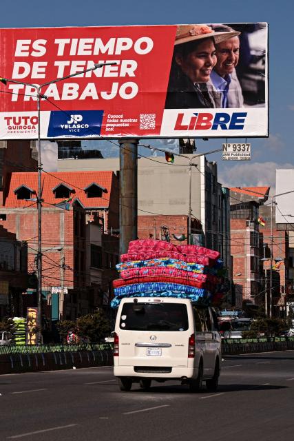 A van passes in front of a billboard for Bolivia's presidential candidate from the "Alianza Libre" (Free Alliance) coalition, Jorge "Tuto" Quiroga Ramirez, in La Paz on August 15, 2025. Bolivia will hold a presidential election on August 17, 2025. (Photo by Martin BERNETTI / AFP)