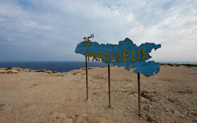 This photograph shows a sign depicting Lampedusa island and reading '35th parallel' in Lampedusa, south Italy on August 16, 2025. (Photo by Stefano RELLANDINI / AFP)