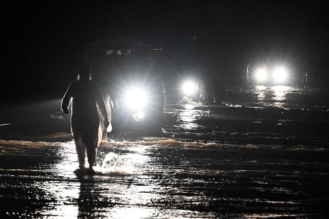 Residents wade through flooded street after a cloudburst in Dolari village, Swabi district, in northern Pakistan's mountainous Khyber Pakhtunkhwa province, on August 18, 2025. Fresh torrential rains in northern Pakistan killed at least 20 people on August 18, local officials said, as the region is ravaged by an unusually intense monsoon season that has left more than 300 people dead in recent days. (Photo by Aamir QURESHI / AFP)