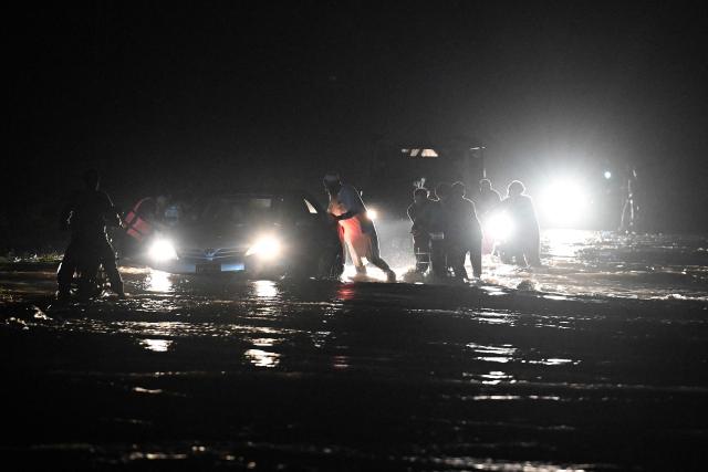 Residents wade through flooded street after a cloudburst in Dolari village, Swabi district, in northern Pakistan's mountainous Khyber Pakhtunkhwa province, on August 18, 2025. Fresh torrential rains in northern Pakistan killed at least 20 people on August 18, local officials said, as the region is ravaged by an unusually intense monsoon season that has left more than 300 people dead in recent days. (Photo by Aamir QURESHI / AFP)
