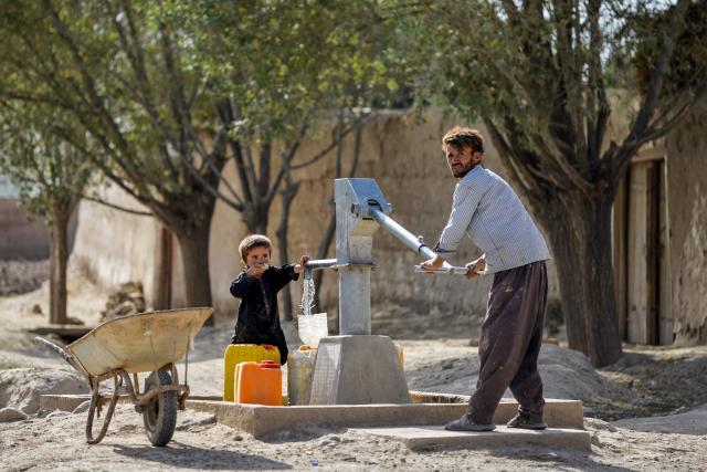 An Afghan man fills cannisters with water from a handpump along a roadside in the Argo district of Badakhshan province on August 19, 2025. (Photo by Omer ABRAR / AFP)