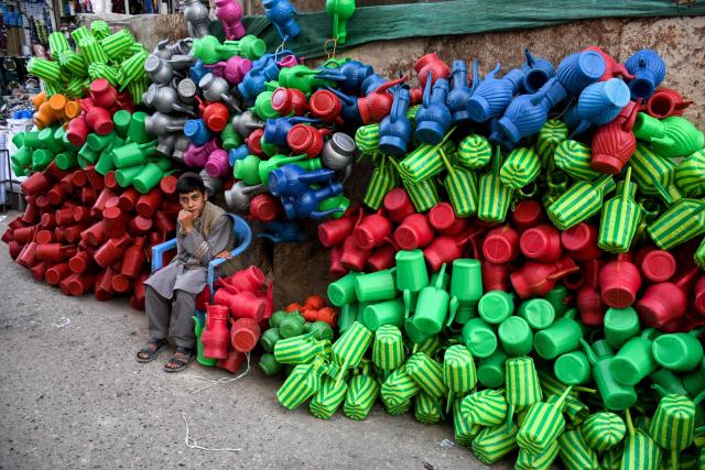 A Afghan boy selling plastic cans waits for customers at a market in Mazar-i-Sharif on August 19, 2025. (Photo by Atif ARYAN / AFP)