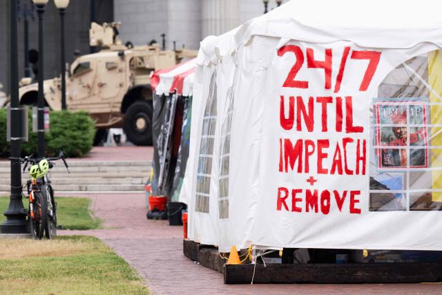 A tent displaying protest messages sits near a military vehicle as National Guard members stand watch outside Union Station in Washington, DC, under orders from the Trump administration on August 19, 2025. US President Donald Trump on August 11 deployed military and federal law enforcement to curb violent crime in Washington, as he seeks to make good on his campaign pledge to be a "law and order" president. The Republican leader said he would place the city's Metropolitan Police under federal government control while also sending the National Guard onto the streets of the US capital. (Photo by SAUL LOEB / AFP)