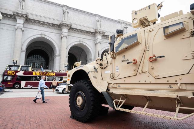People walk past a military vehicle stationned outside Union Station in Washington, DC, under orders from the Trump administration on August 19, 2025. US President Donald Trump on August 11 deployed military and federal law enforcement to curb violent crime in Washington, as he seeks to make good on his campaign pledge to be a "law and order" president. The Republican leader said he would place the city's Metropolitan Police under federal government control while also sending the National Guard onto the streets of the US capital. (Photo by SAUL LOEB / AFP)