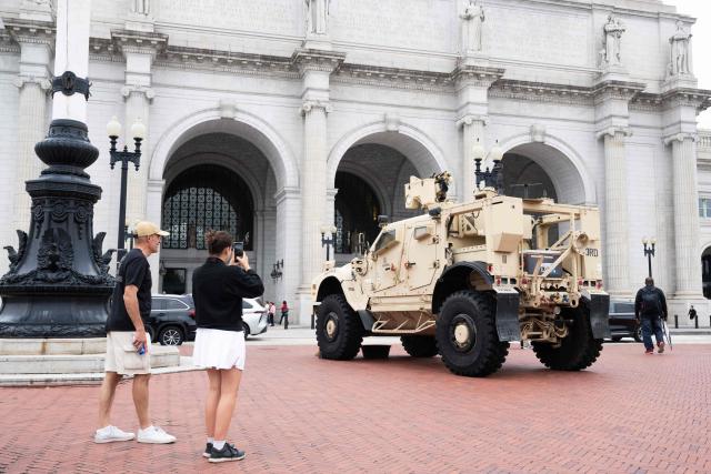 People photograph military vehicles as members of the National Guard stand watch outside of Union Station in Washington, DC, under orders from the Trump administration on August 19, 2025. US President Donald Trump on August 11 deployed military and federal law enforcement to curb violent crime in Washington, as he seeks to make good on his campaign pledge to be a "law and order" president. The Republican leader said he would place the city's Metropolitan Police under federal government control while also sending the National Guard onto the streets of the US capital. (Photo by SAUL LOEB / AFP)