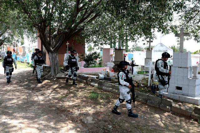 Members of the National Guard walk through San Sebastianito the San Sebastianito cemetery, as Attorney General's Officers inspect the area after the collective “Madres Buscadoras de Jalisco” reported the discovery of a clandestine mass grave in Tlaquepaque, Jalisco state, Mexico on August 18, 2025. (Photo by AFP)