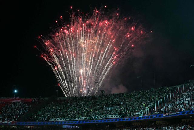 Fireworks are pictured behind Atletico Nacional fans before the Copa Libertadores round of 16 second leg football match between Brazil's Sao Paulo and Colombia's Atletico Nacional at the Morumbi Stadium in Sao Paulo, Brazil on August 19, 2025. (Photo by NELSON ALMEIDA / AFP)