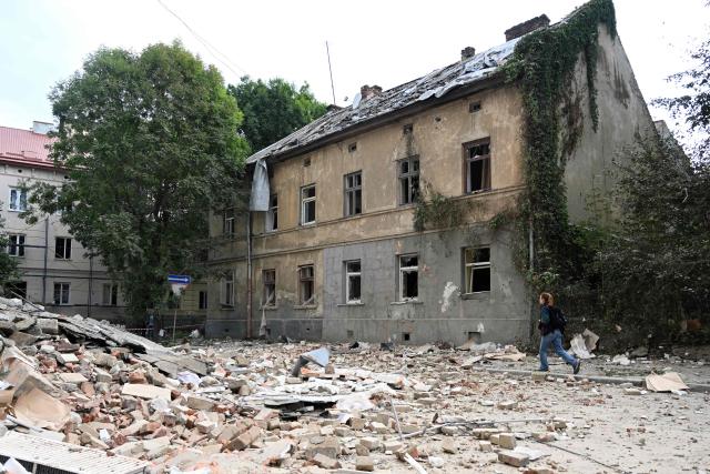 A person walks past a residential building damaged following Russian air attacks in the western Ukrainian city of Lviv on August 21, 2025, amid the Russian invasion of Ukraine. Russia launched hundreds of drones and missiles at Ukraine overnight, the Ukrainian air force said on August 21, 2025, Moscow's largest attack in weeks after US-led efforts to halt the Kremlin's invasion. (Photo by YURIY DYACHYSHYN / AFP)
