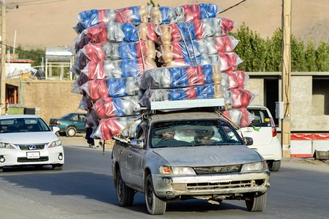 An Afghan man drives a car laden with plastic canisters along a road in the Fayzabad district of Badakhshan province on August 21, 2025. (Photo by Omer ABRAR / AFP)