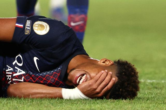 Paris Saint-Germain's French midfielder #14 Desire Doue lies on the football pitch after a foul during the French L1 football match between Paris Saint-Germain (PSG) and Angers SCO at the Parc des Princes Stadium in Paris on August 22, 2025. (Photo by FRANCK FIFE / AFP)