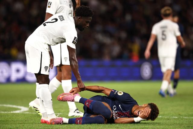 Paris Saint-Germain's French midfielder #14 Desire Doue lies on the football pitch after a fool, next to Angers' Haitian defender #02 Carlens Arcus (L), during the French L1 football match between Paris Saint-Germain (PSG) and Angers SCO at the Parc des Princes Stadium in Paris on August 22, 2025. (Photo by FRANCK FIFE / AFP)