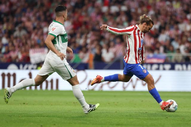 Atletico Madrid's French forward #07 Antoine Griezmann kicks the ball next to Elche's Portuguese midfielder #16 Martim Neto during the Spanish league football match between Club Atletico de Madrid and Elche CF at Metropolitano Stadium in Madrid on August 23, 2025. (Photo by Thomas COEX / AFP)