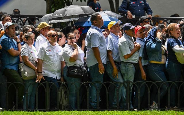 Residents and public sector workers line up during the Bolivarian militia enlistment process at Bolivar square in Caracas on August 23, 2025. Thousands of people enlisted in Venezuela's military forces on Saturday to join the ranks in preparation for a possible US invasion. (Photo by Juan BARRETO / AFP)