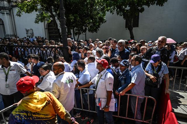 People line up during the Bolivarian militia enlistment process at Bolivar square in Caracas on August 23, 2025. Thousands of people enlisted in Venezuela's military forces on Saturday to join the ranks in preparation for a possible US invasion. (Photo by Juan BARRETO / AFP)
