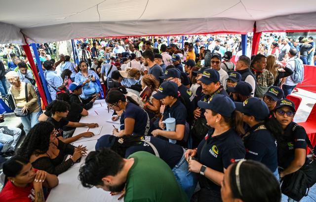 People line up during the Bolivarian militia enlistment process at Bolivar square in Caracas on August 23, 2025. Thousands of people enlisted in Venezuela's military forces on Saturday to join the ranks in preparation for a possible US invasion. (Photo by Juan BARRETO / AFP)