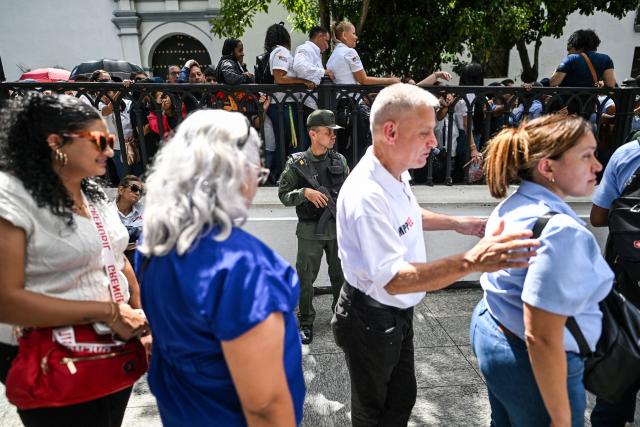 People line up during the Bolivarian militia enlistment process at Bolivar square in Caracas on August 23, 2025. Thousands of people enlisted in Venezuela's military forces on Saturday to join the ranks in preparation for a possible US invasion. (Photo by Juan BARRETO / AFP)