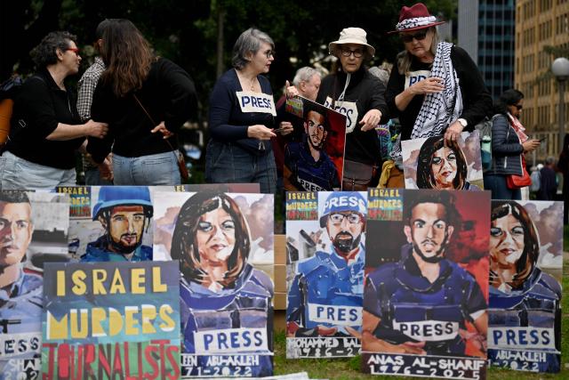 Demonstrators arrange artwork depicting journalists who were killed while performing their duties in Gaza, as they take part in a pro-Palestinian rally against Israel's actions and ongoing food shortages in the Gaza Strip, which the UN officially declared a famine on August 22, during a protest in Sydney's central business district on August 24, 2025. (Photo by Saeed KHAN / AFP)