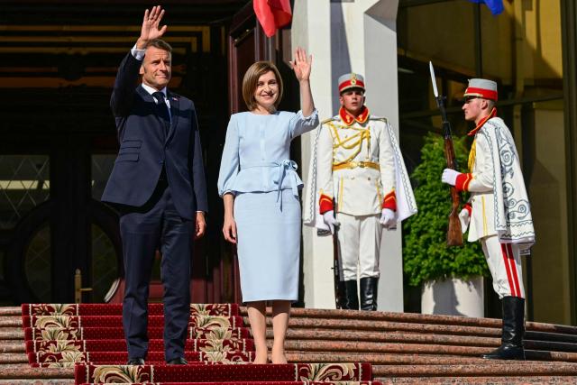 Moldova's President Maia Sandu (2nd-L) welcomes France's President Emmanuel Macron as they wave, in Chisinau on August 27, 2025, during Moldova's 34th Independence Day celebrations. The leaders of France, Germany and Poland arrive in Moldova in a show of support, a day before campaigning starts for next month's tense parliamentary election amid claims of Russian interference in the pro-EU nation bordering Ukraine. (Photo by Daniel MIHAILESCU / AFP)
