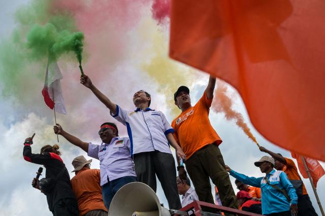 Workers sing while setting off colourful smoke flares during a demonstration outside the Parliament building in Jakarta on August 28, 2025, demanding fairness from lawmakers who seek to raise their own allowances while workers’ calls for wage increases are ignored. (Photo by BAY ISMOYO / AFP)