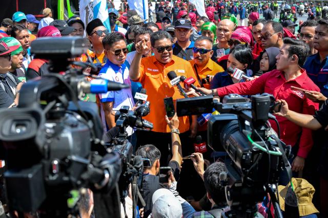Labour union president Said Iqbal (C) speaks to the media as workers demonstrate outside the Parliament building in Jakarta on August 28, 2025, demanding fairness from lawmakers who seek to raise their own allowances while workers’ calls for wage increases are ignored. (Photo by BAY ISMOYO / AFP)