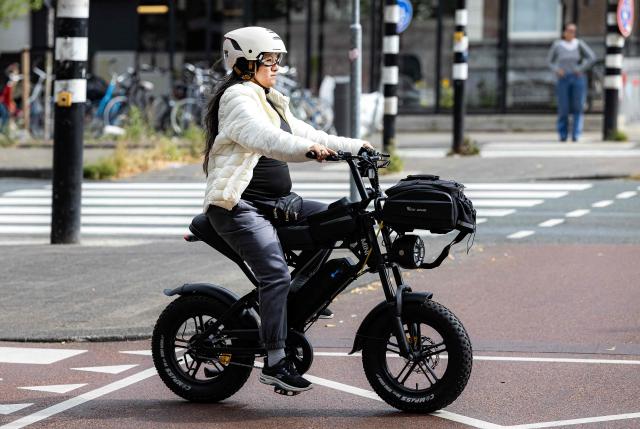 A cyclist wearing a helmet rides an electric bicycle in Amsterdam, on August 28, 2025. (Photo by Ramon van Flymen / ANP / AFP) / Netherlands OUT
