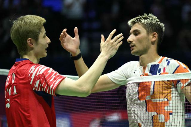 China's Shi Yu Qi (L) shakes hands with France's Christo Popov at the end of their men's single match at the Badminton BWF World Championships at the Adidas Arena in Paris, on August 28, 2025. (Photo by Bertrand GUAY / AFP)