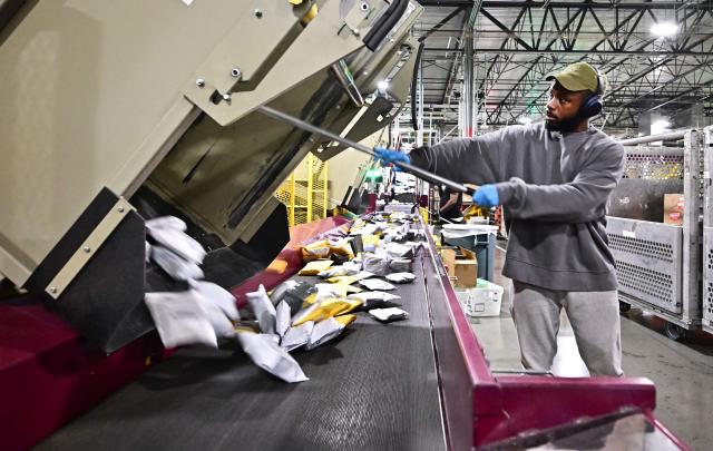 (FILES) Postal workers sort through mail and packages during a media tour hosted by the US Postal Service at the Los Angeles Processing and Distribution Center, the largest in the country, equivalent to 29 football fields, on November 30, 2023. The United States on August 29, 2025 ended tariff exemptions on small packages entering the country from abroad, in a move that has sparked concern among small businesses and warnings of consumer price hikes. (Photo by Frederic J. BROWN / AFP)