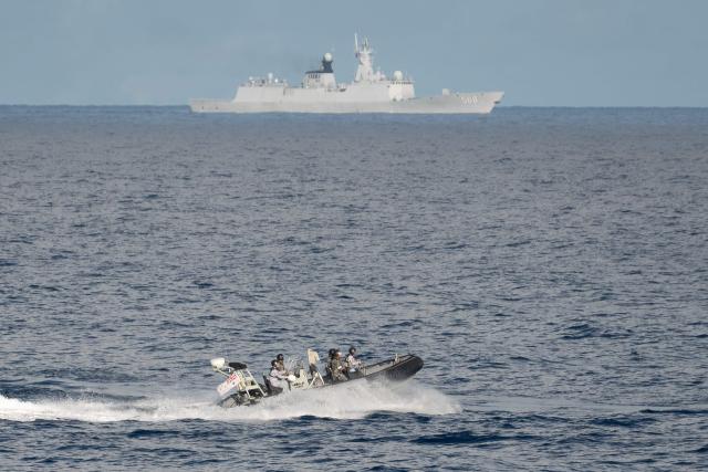 A Chinese PLA Navy ship (back) is seen past Royal Australian Navy sailors aboard their inflatable rigid hull boat during a maritime cooperative activity between the Philippines, Australia and Canadian navies near Scarborough Shoal in disputed waters of the South China Sea on September 3, 2025. (Photo by Ted ALJIBE / AFP)