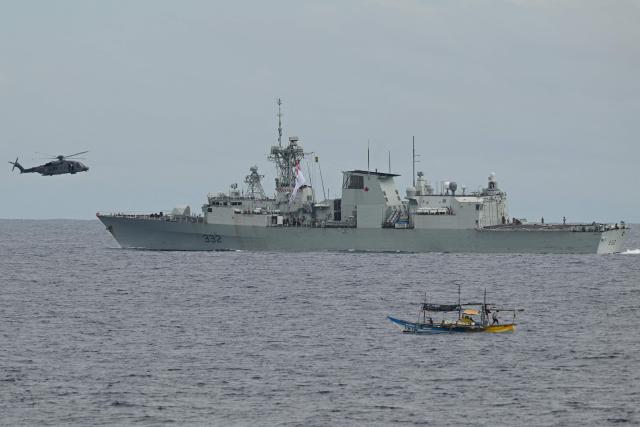 A CH-148 Cyclone helicopter approaches the Royal Canadian Navy frigate HMCS Ville de Quebec for landing as a small Philippine fishing boat (front R) is seen during a maritime cooperative activity between the Philippines, Australia and Canadian navies near Scarborough Shoal in disputed waters of the South China Sea on September 2, 2025.  (Photo by Ted ALJIBE / AFP)