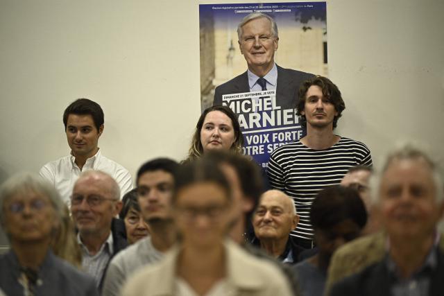 Supporters attend a campaign meeting of former Prime minister Michel Barnier (poster) for the parliamentary by-elections for Paris' 2nd electoral circonscription in Paris, on September 4, 2025. (Photo by JULIEN DE ROSA / AFP)