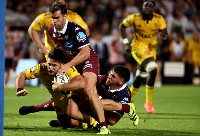 La Rochelle' French centre Jules Favre (bottom L) is tackled by Bordeaux' French wing Damian Penaud (Top) and Bordeaux' French lock Cyril Cazeaux (bottom R) during the French Top14 rugby union match between Union Bordeaux-Begles (UBB) and Stade Rochelais at The Chaban-Delmas Stadium in Bordeaux, south-western France, on September 6, 2025. (Photo by ROMAIN PERROCHEAU / AFP)