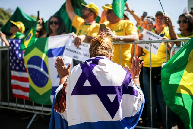 A supporter of Brazil's former president (2019-2022) Jair Bolsonaro, wrapped in an Israeli flag prays during a demonstration during Independence Day, in Brasilia on September 7, 2025. Bolsonaro will test his political strength with demonstrations in the country's main cities, days before the Supreme Court deliver its verdict. The far-right leader, also a former army captain, risks up to 43 years in prison if convicted of attempting to cling to power after losing 2022 elections to his leftist rival Luiz Inacio Lula da Silva. (Photo by Arthur Menescal / AFP)