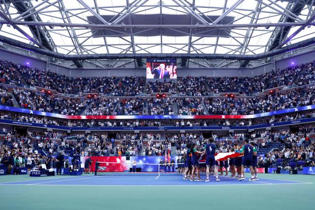 US President Donald Trump is seen on a screen saluting as the national anthem is played during the men's singles final tennis match between Spain’s Carlos Alcaraz and Italy’s Jannik Sinner on the last day of the US Open tennis tournament at the USTA Billie Jean King National Tennis Center in New York City, on September 7, 2025. (Photo by kena betancur / AFP)