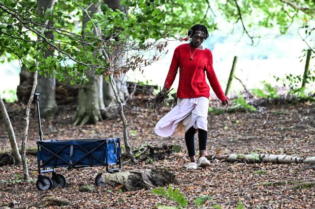 A woman identifying herself as handmaiden 'Asnat' from the 'Kingdom of Kubala' gathers supplies from the wood where they have set up camp near Jedburgh in the Scottish Borders on September 8, 2025 on what they say is their ancestral land. 'King Atehene', 'Queen Nandi' and their handmaiden 'Asnat' have set up camp near Jedburgh claiming land that they say belonged hundreds of years ago to the 'Kingdom of Kubala'. Local residents have been bringing supplies to help the three after their first camp was reportedly destroyed. The group have reportedly recieved a notice of eviction by the council. (Photo by Andy Buchanan / AFP)