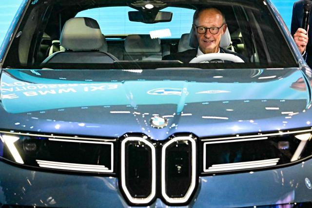 German Chancellor Friedrich Merz is seated in BMW IX3 car at the German car manufacturers booth on the opening day of the International Motor Show IAA, September 9, 2025, in Munich, southern Germany. The IAA Mobility fair runs from September 9 to 14, 2025. (Photo by Tobias SCHWARZ / AFP)