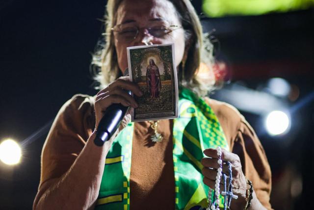 A supporter of Brazil's former President Jair Bolsonaro shows a small picture of Our Lady of Tears near his residence in Brasilia on September 9, 2025. Bolsonaro, 70, risks a prison term of over 40 years if found guilty of seeking to stay in power after his defeat in 2022 elections to leftist Luiz Inacio Lula da Silva. (Photo by Arthur MENESCAL / AFP)