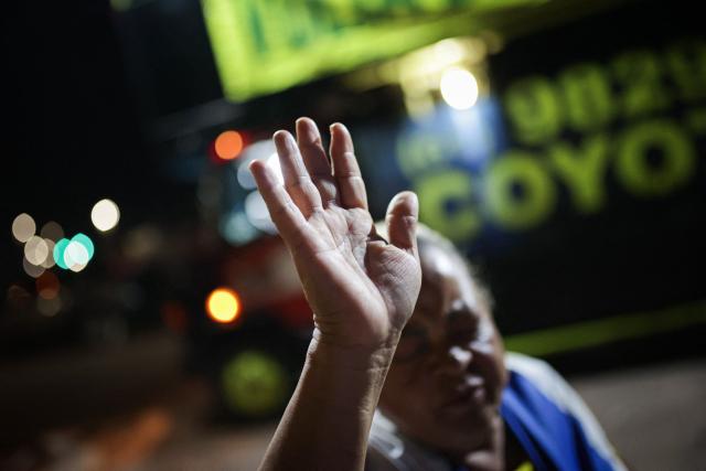 A supporter of Brazil's former President Jair Bolsonaro prays near his residence in Brasilia on September 9, 2025. Bolsonaro, 70, risks a prison term of over 40 years if found guilty of seeking to stay in power after his defeat in 2022 elections to leftist Luiz Inacio Lula da Silva. (Photo by Arthur MENESCAL / AFP)