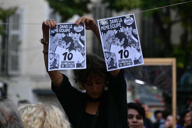 A protester hangs up leaflets during a demonstration as part of the "Bloquons tout" ("Let's block everything") protest movement, at the top of the Canebiere avenue in Marseille, southern France, on September 10, 2025. The broad anti-government campaign, dubbed "Bloquons tout" ("Let's block everything"), calls for a a shutdown of France on September 10 with a string of protest actions and civil disobedience around the country, while the handover of power between the new Prime Minister and his predecessor, who suffered a crushing loss in a confidence vote on September 8, is scheduled for the same day at noon. (Photo by Christophe SIMON / AFP)