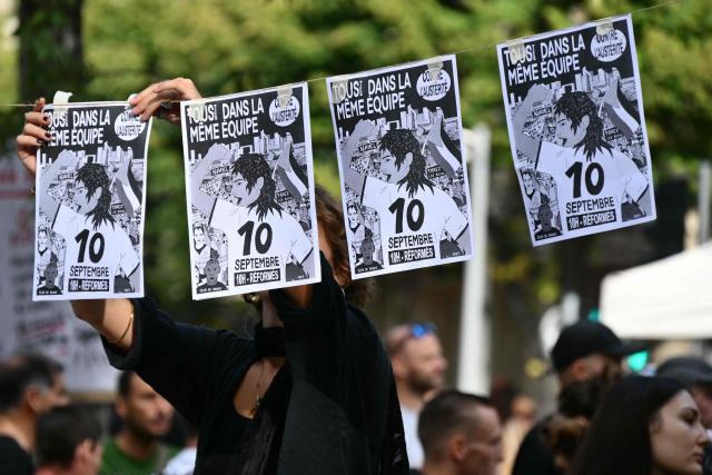 A protester hangs up leaflets during a demonstration as part of the "Bloquons tout" ("Let's block everything") protest movement, at the top of the Canebiere avenue in Marseille, southern France, on September 10, 2025. The broad anti-government campaign, dubbed "Bloquons tout" ("Let's block everything"), calls for a a shutdown of France on September 10 with a string of protest actions and civil disobedience around the country, while the handover of power between the new Prime Minister and his predecessor, who suffered a crushing loss in a confidence vote on September 8, is scheduled for the same day at noon. (Photo by Christophe SIMON / AFP)