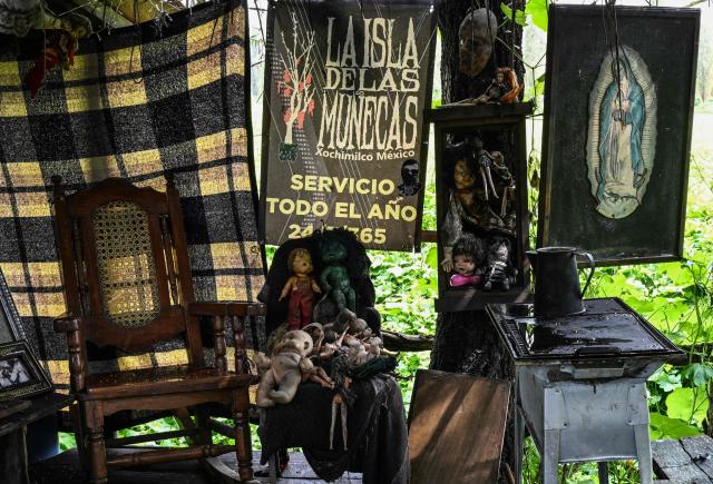 Old and deteriorated dolls hang on a wall next to a poster of the Virgin of Guadalupe at Isla de las Munecas (Island of the Dolls) in Xochimilco, Mexico on September 10, 2025. Naked or tattered plastic bodies hang from ancient trees. Severed heads, glass eyes staring at visitors. The macabre Island of the Dolls in Mexico City frightens many, but fascinated Lady Gaga and Tim Burton.. (Photo by Yuri CORTEZ / AFP)