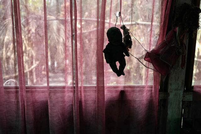 An old and deteriorated doll hangs on a stick at Isla de las Munecas (Island of the Dolls) in Xochimilco, Mexico on September 10, 2025. Naked or tattered plastic bodies hang from ancient trees. Severed heads, glass eyes staring at visitors. The macabre Island of the Dolls in Mexico City frightens many, but fascinated Lady Gaga and Tim Burton.. (Photo by Yuri CORTEZ / AFP)