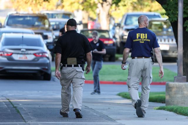 Law enforcement officials, including a member of the FBI (R), work near the crime scene where political activist Charlie Kirk was shot at Utah Valley University in Orem, Utah, on September 11, 2025. The gunman who shot dead US right-wing youth leader Charlie Kirk in a targeted killing remained at large Thursday but authorities said they have video images of the suspect and have recovered a "high-powered" rifle. Kirk, a 31-year-old superstar on the Republican right who was credited with helping Donald Trump return to the presidency last year, was shot while addressing a large crowd at Utah Valley University on Wednesday. (Photo by Patrick T. Fallon / AFP)