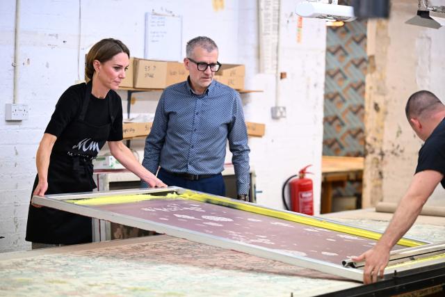 Britain's Catherine, Princess of Wales lifts a screen printing frame during a visit to Marina Mill in Cuxton, south east England on September 11, 2025. Marina Mill was established in 1967, and is based in an old Victorian mill on the banks of the River Medway, where a small team produces fabrics using the traditional silk-screen method. (Photo by Chris J Ratcliffe / POOL / AFP)
