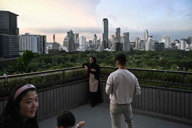 Visitors take pictures from a rooftop garden on top of Dusit Central Park shopping mall in Bangkok on September 11, 2025. (Photo by Lillian SUWANRUMPHA / AFP)
